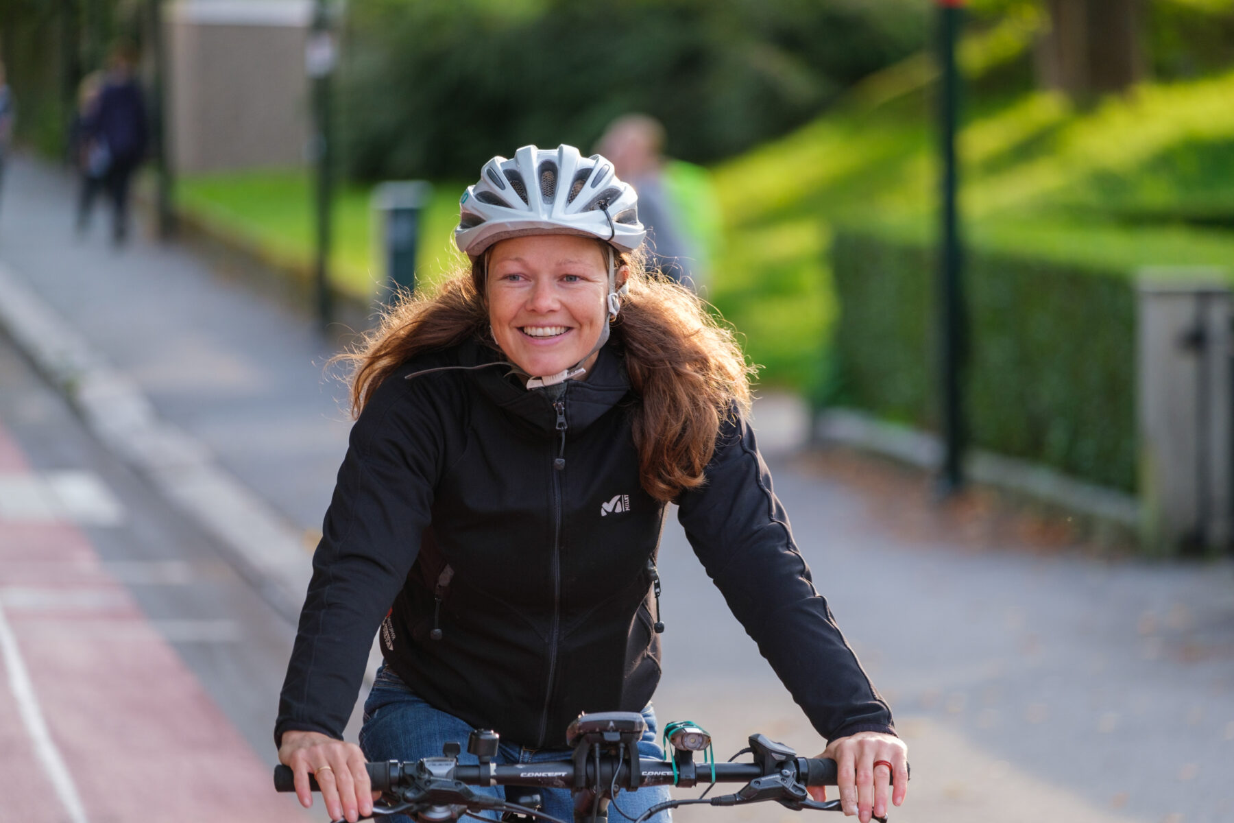 Blid kvinne som sykler i bybildet